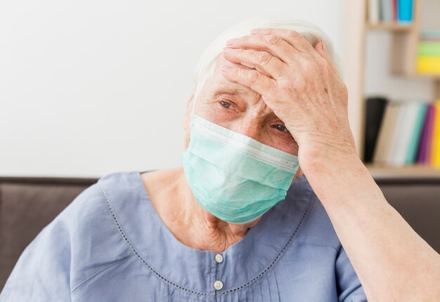 Front view of elder woman with medical mask feeling ill