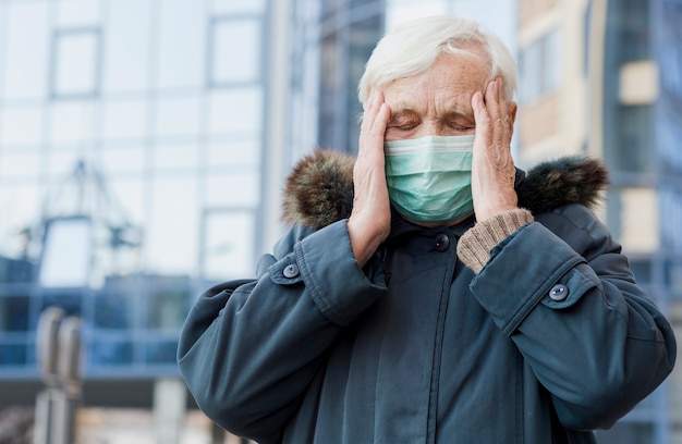 Front view of elder woman with medical mask not feeling well while being outside