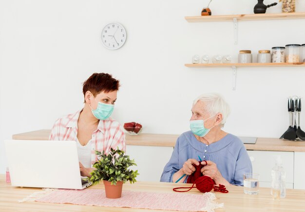 Front view of elder women wearing medical masks at home while doing activities