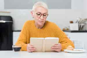 Free photo front view of elderly woman reading a book