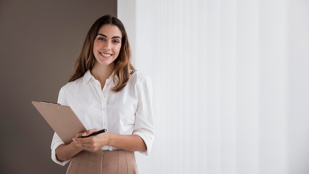 Free photo front view of elegant businesswoman holding clipboard with copy space