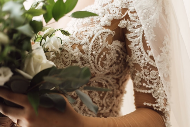 Free photo front view of embroidery on the corset of  wedding dress and wedding bouquet of white eustomas