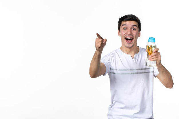 Front view excited young male holding bottle of lemonade and pointing on white background juice fresh horizontal human soda liquid ice skin fruit drink