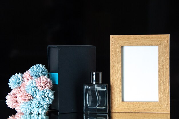 Front view expensive perfume with flowers and picture frame on a black table