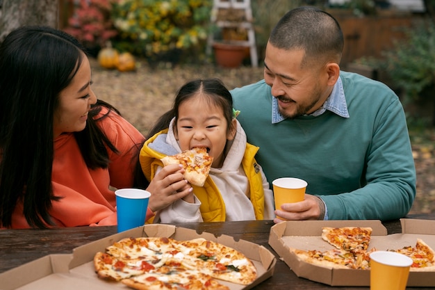 Free photo front view family eating pizza outdoors