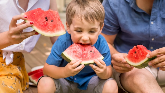 Front view family eating together watermelon