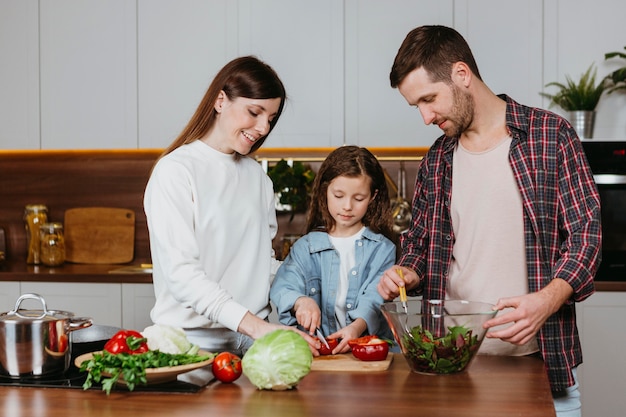 Front view of family preparing food in the kitchen at home