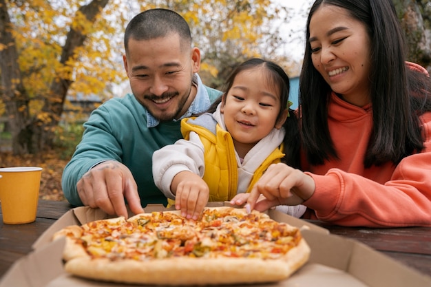 Front view family with tasty pizza outside