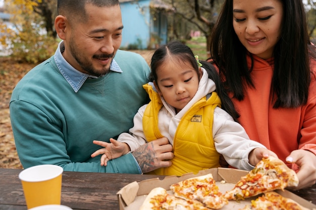 Free photo front view family with tasty pizza outside