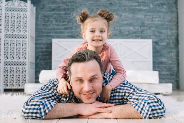 Front view of father carrying his daughter on back at home