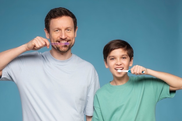 Free photo front view father and kid brushing teeth