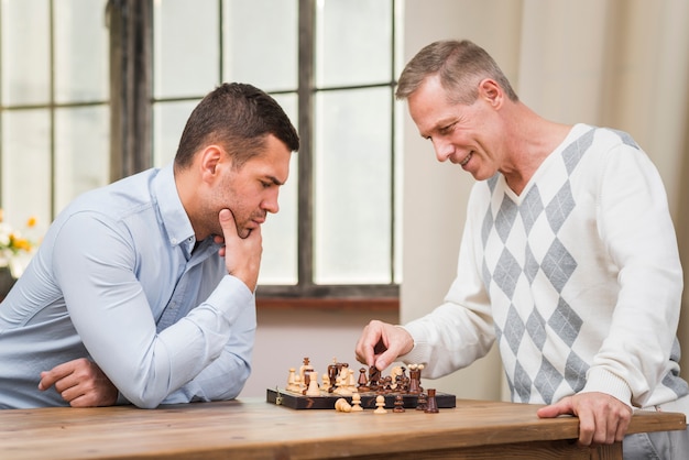 Free photo front view of father and son playing chess