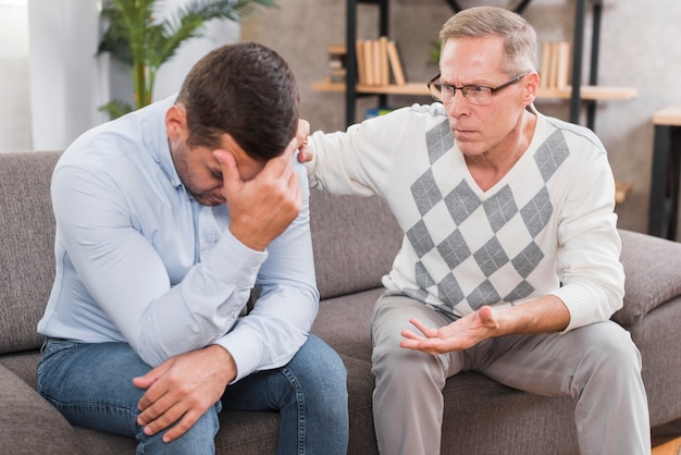 Free photo front view of father and son sitting on couch