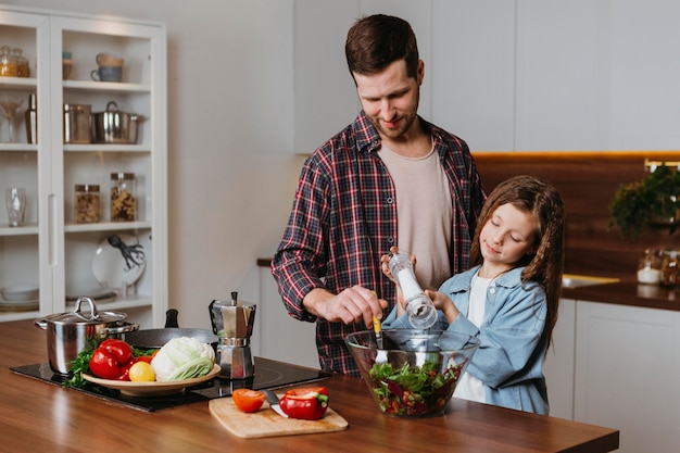 Front view of father with daughter preparing food in the kitchen