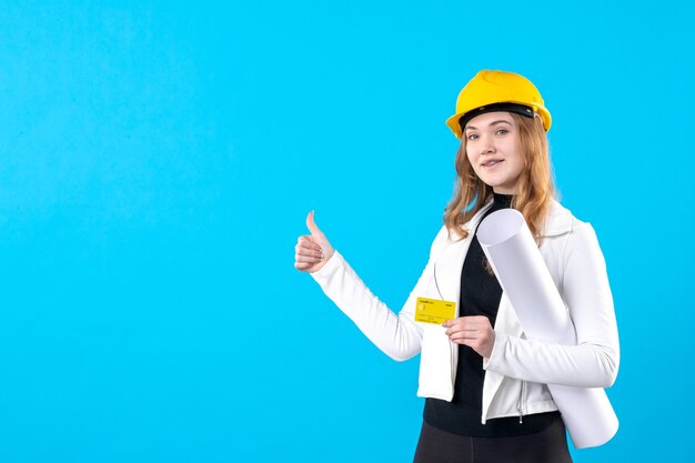 Front view female architect holding plan and bank card on a blue