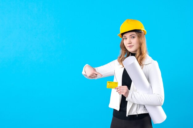 Front view female architect holding plan and bank card on blue