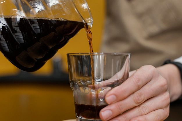 Free photo front view of female barista pouring coffee in transparent glass