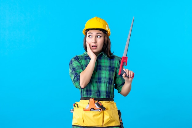 Front view female builder holding little saw on blue