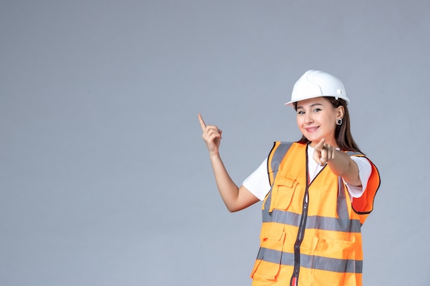 Front view of female builder in uniform on gray wall