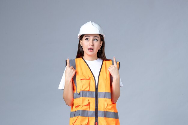 Front view of female builder in uniform on gray wall