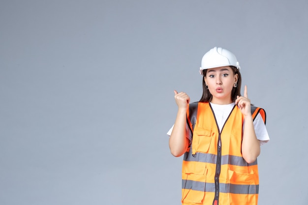 Front view of female builder in uniform on gray wall