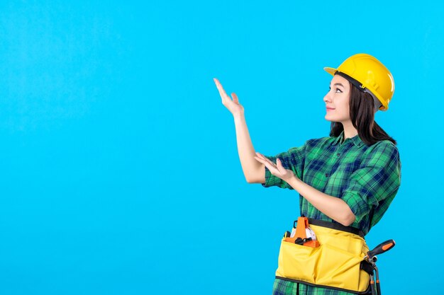 Front view female builder in uniform and helmet on blue