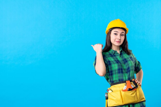 Front view female builder in uniform and helmet on blue