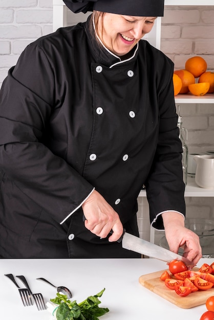 Free photo front view of female chef chopping tomatoes