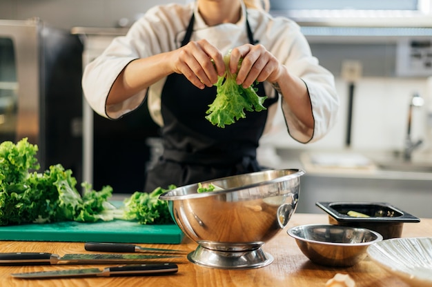 Free photo front view of female chef tearing salad in the kitchen