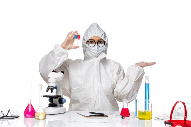 Front view female chemist in special protective suit holding empty flasks on the light-white background virus health chemistry covid