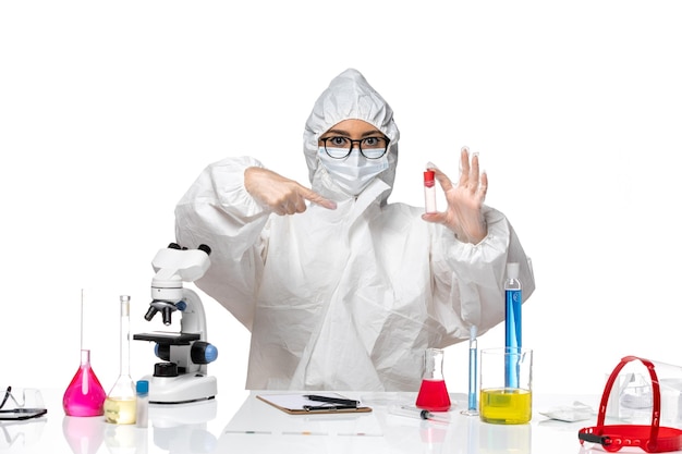 Front view female chemist in special protective suit holding flask on the white background virus health chemistry covid-