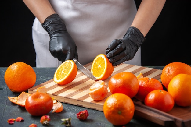 Free Photo front view female cook cutting orange on a dark salad health meal food job vegetable fresh drink fruit diet