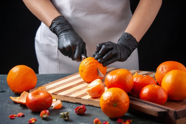 Free photo front view female cook cutting orange on dark salad health meal food job vegetable fresh drink fruit diet