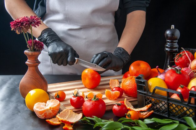 Front view female cook cutting tangerines on dark cooking salad health diet vegetable meal food fruit job