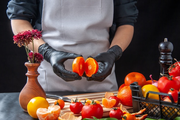 Front view female cook cutting tangerines on dark cooking salad health diet vegetable meal food fruits job