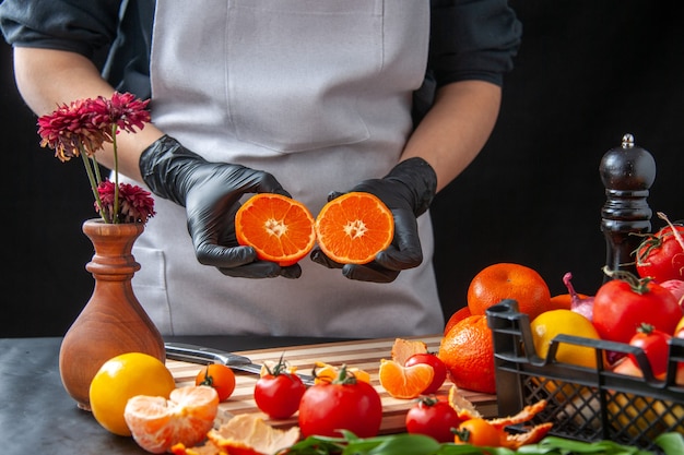 Front view female cook holding half sliced tangerines on dark cooking salad health vegetable meal food fruit job diet