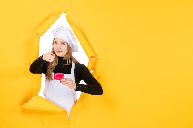 Front view female cook holding red bank card on yellow photo emotion food kitchen cuisine color money job