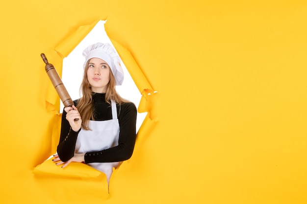 Front view female cook holding rolling pin on yellow kitchen job color cuisine sun photo