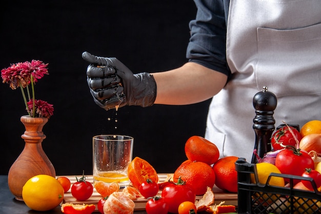 Front view female cook making tangerine juice on a black salad health meal food job vegetable fresh drink fruit diet