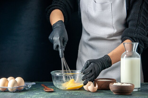 Front view female cook mixing eggs for dough on dark pastry cake pie worker cuisine job hotcake