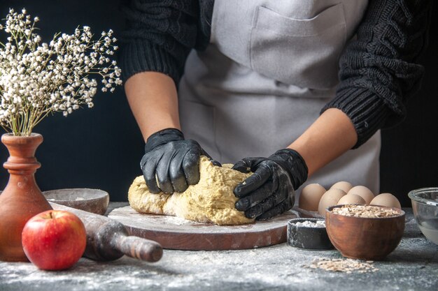 Front view female cook rolling out dough on dark cuisine job pastry hotcake egg kitchen dough