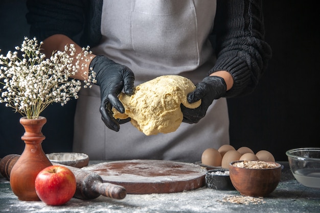 Front view female cook rolling out dough on a dark job raw dough pie oven pastry hotcake bakery egg