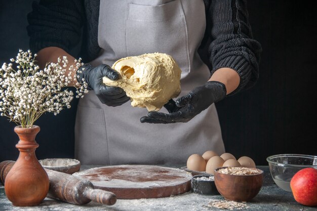 Front view female cook rolling out dough on dark job raw dough pie oven pastry hotcake bakery egg