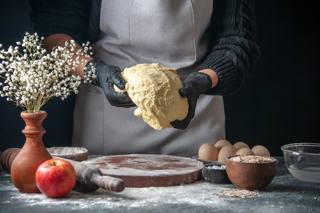 Front view female cook rolling out dough on the dark job raw dough pie oven pastry hotcake bakery egg