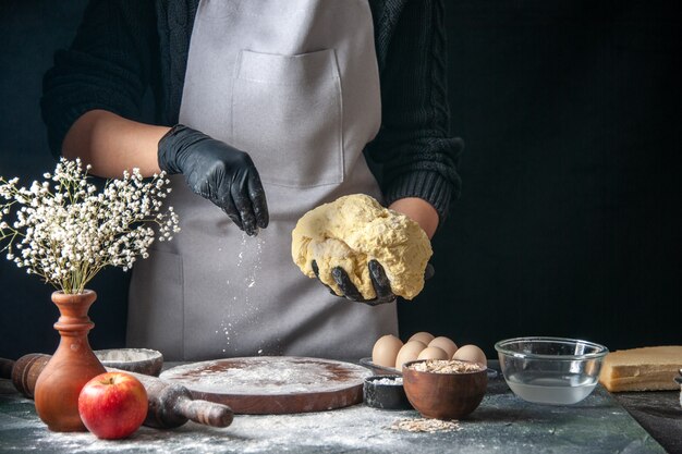 Front view female cook rolling out dough on dark job raw dough pie oven pastry hotcakes bakery egg