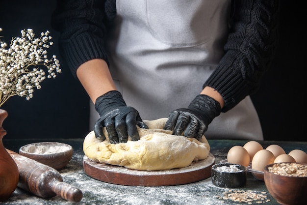 Free photo front view female cook rolling out dough on a dark pastry job raw dough hotcake bakery pie oven