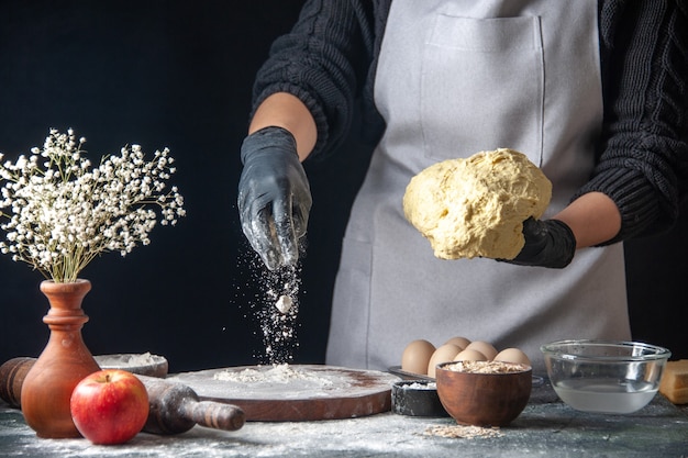 Free photo front view female cook rolling out dough with flour on a dark job dough pastry kitchen hotcake cuisine bakery egg