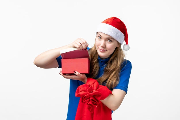 Front view of female courier opening holiday present on white wall