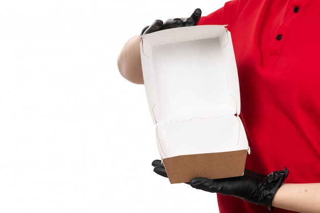 Free photo a front view female courier in red shirt and black gloves holding empty food package