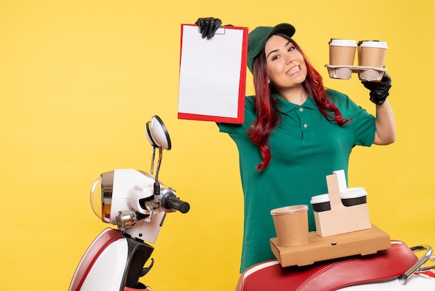 Free photo front view of female courier with file note and coffee on a yellow wall